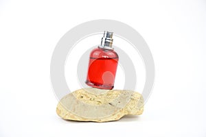 Unbranded perfume spray red bottle on stone isolated on white background. Mockup, template