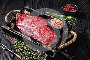 Unccoked rump steak or raw top sirloin beef meat steak. Black wooden background. Top view