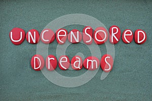 Uncensored Dreams, creative logo composed with red colored stone letters over green sand