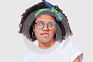 Uncertain African American woman has puzzled expression, frowns her face and looking up. Close-up portrait of doubtful dark