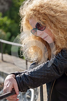 uncertain  indecisive  mature woman with sunglasses and red hair looks down  doubtful  hesitant  on vacation in italy