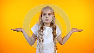 Uncertain preteen girl lifting hands in dismay isolated on yellow background photo
