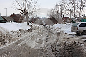 an unclean dirt road with a track is littered with snow in the village there is no passage in the spring