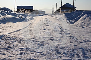 Unclean snow-covered road access to houses in  Siberian village in winter photo