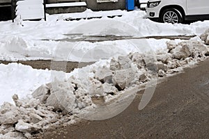 Uncleaned streets with heavy snowdrifts after snowfall in the city, cars under the snow