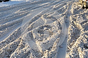 Uncleared road covered with dirty snow with traces of cars