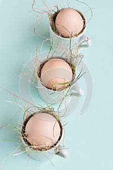 Uncolored natural easter eggs in espresso cups; happy easter concept; green minimalist easter