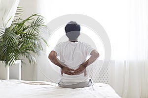 Uncomfortable Bed. Young Male Suffering Lower Back Pain After Waking Up