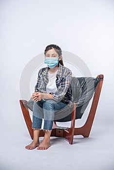 An uncomfortable woman sitting on a chair and wearing a mask