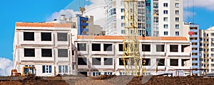 Uncompleted building on construction site with ground tractor and crane