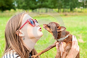 Unconditional love. Teenage girl kissing her brown toy-terrier d