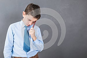 Unconfident boy student before dark background with copy-space a