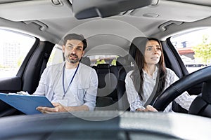 Unconfident millennial pretty woman driving car with instructor