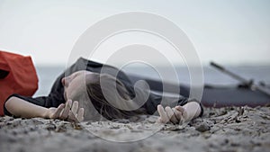 Unconscious woman lying on seashore, drowned swimmer, victim of shipwreck photo