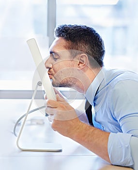 Unconventional office romance. Humorous shot of a businessman kissing his monitor.