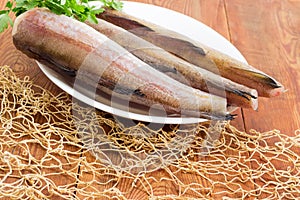 Uncooked Alaska pollock carcasses on wooden surface with fishing