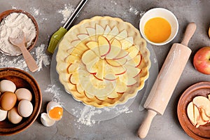 Uncooked apple pie with ingredients on table