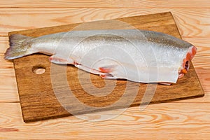 Uncooked arctic char carcass on cutting board on rustic table