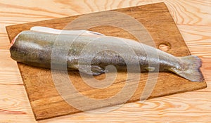 Uncooked arctic char carcass on cutting board on rustic table