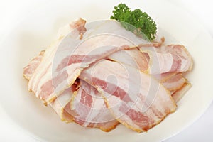 Uncooked bacon on white plate