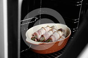 Uncooked bacon wrapped asparagus in baking dish on oven rack