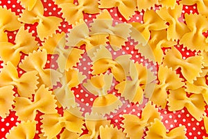 Uncooked bow tie farfalle pasta on red background