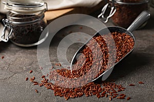 Uncooked brown rice in metal scoop on table