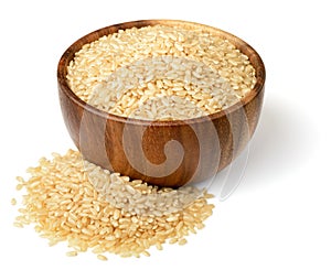 Uncooked brown rice in the wooen bowl, isolated on the white background