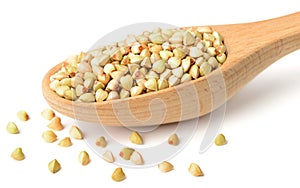 Uncooked buckwheat in the wooden spoon, isolated on the white background.