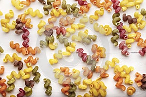 uncooked colorful pasta scattered as a background on a white background.