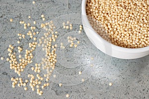 Uncooked corner view millet in white ceramic bowl on metal background