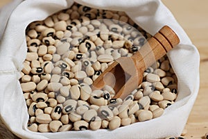 Uncooked Dried Black Eyed Peas in Bag With Wooden Scoop