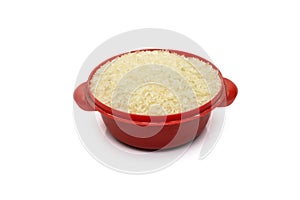 Uncooked dry rice on a small dirty red toy bowl on an isolated white background