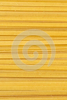 Uncooked durum fettuccine pasta background. Close up of raw spaghetti. Full frame of noodles