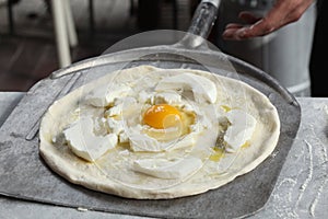 Uncooked egg and mozzarella pizza on a pizza shovel ready for the oven with copy space for your text