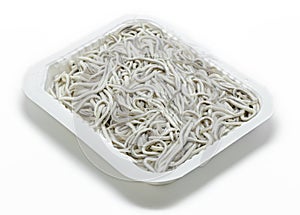 Uncooked Elvers (baby eels) in plastic tray on white