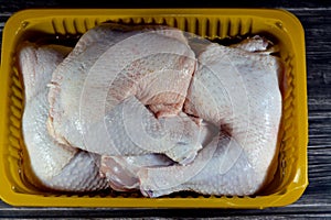 uncooked fresh raw chicken legs drumsticks and thighs hindquarter leg quarters with skin and bones in a yellow disposable plate