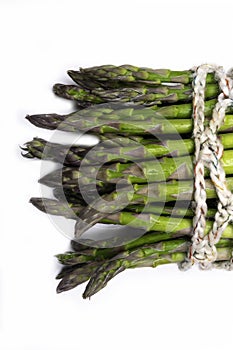 uncooked green asparagus tied with twine, isolated on white