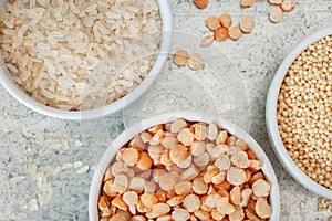 Uncooked half peas, millet and rice in white ceramic bowl on metal background macro