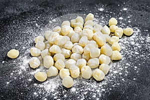 Uncooked homemade gnocchi on black cutting board. Black background. Top view