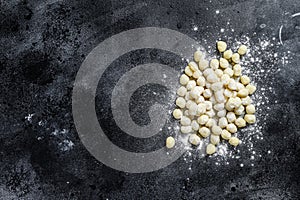 Uncooked homemade gnocchi on black cutting board. Black background. Top view. Copy space