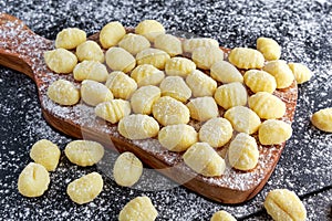 Uncooked homemade gnocchi on wooden cutting floured board