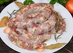 Uncooked homemade pork sausages and spices on dish, close-up