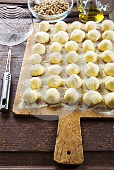 Uncooked homemade potato gnocchi and strainer on vintage cutting