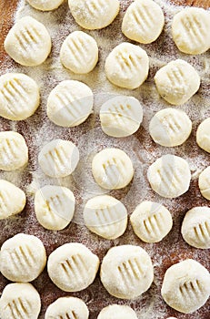 Uncooked homemade potato gnocchi and strainer on vintage cutting