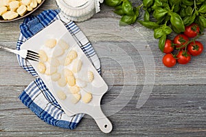 Uncooked homemade potato gnocchi with tomatoes or mushrooms with flour