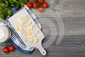 Uncooked homemade potato gnocchi with tomatoes or mushrooms with flour