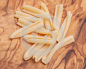 Uncooked Italian Casarecce pasta made from organic durum wheat semolina on natural olive wood cutting board. Macaroni.