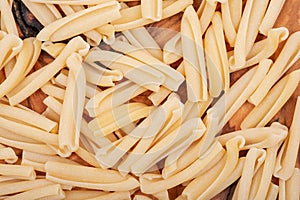 Uncooked Italian Casarecce pasta made from organic durum wheat semolina on natural olive wood cutting board. Macaroni.