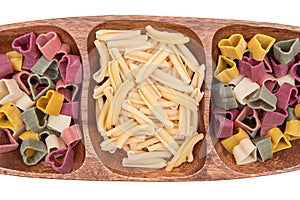 Uncooked Italian Durum wheat semolina heart-shaped and Casarecce pasta arranged on a olive wood plate.